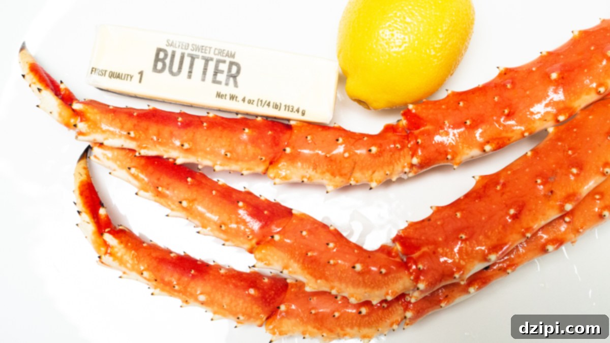 A cluster of king crab legs sit on a white platter next to a stick of butter and a lemon, ready for cooking.