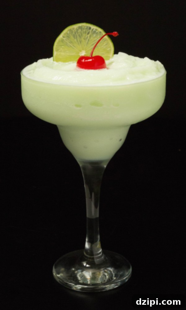A vibrant green Lime Sherbet Margarita in a tall, elegant glass, resting on a sleek black background, garnished with a fresh lime wedge and a maraschino cherry.