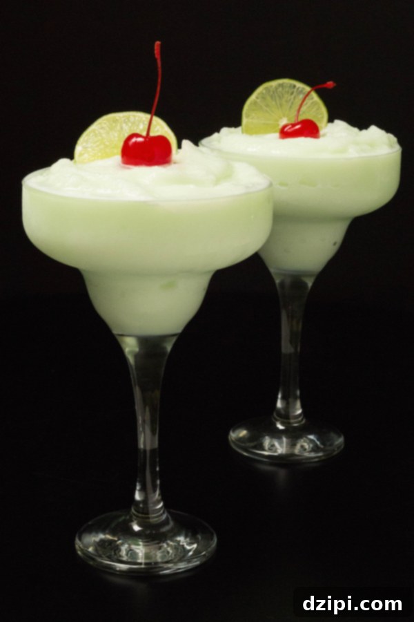 Two vibrant green Lime Sherbet Margaritas presented in classic tall margarita glasses, set against a chic black background.