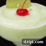 A vibrant Lime Sherbet Margarita garnished with a cherry and a lime slice.