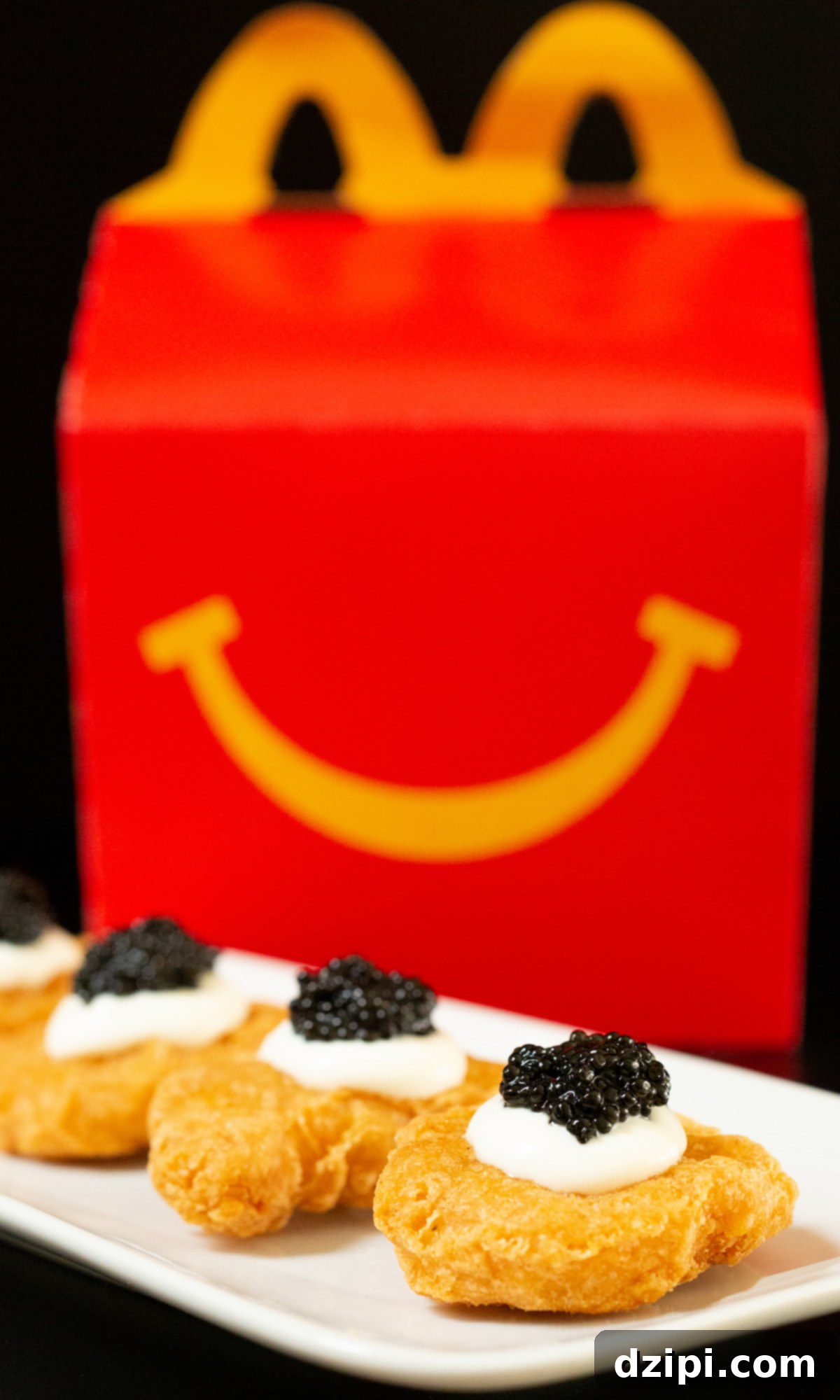 Serving Caviar: A Connoisseur's Guide 5 McDonald's McNuggets topped with crème fraîche and caviar, presented on a small white plate with a Happy Meal box in the background.