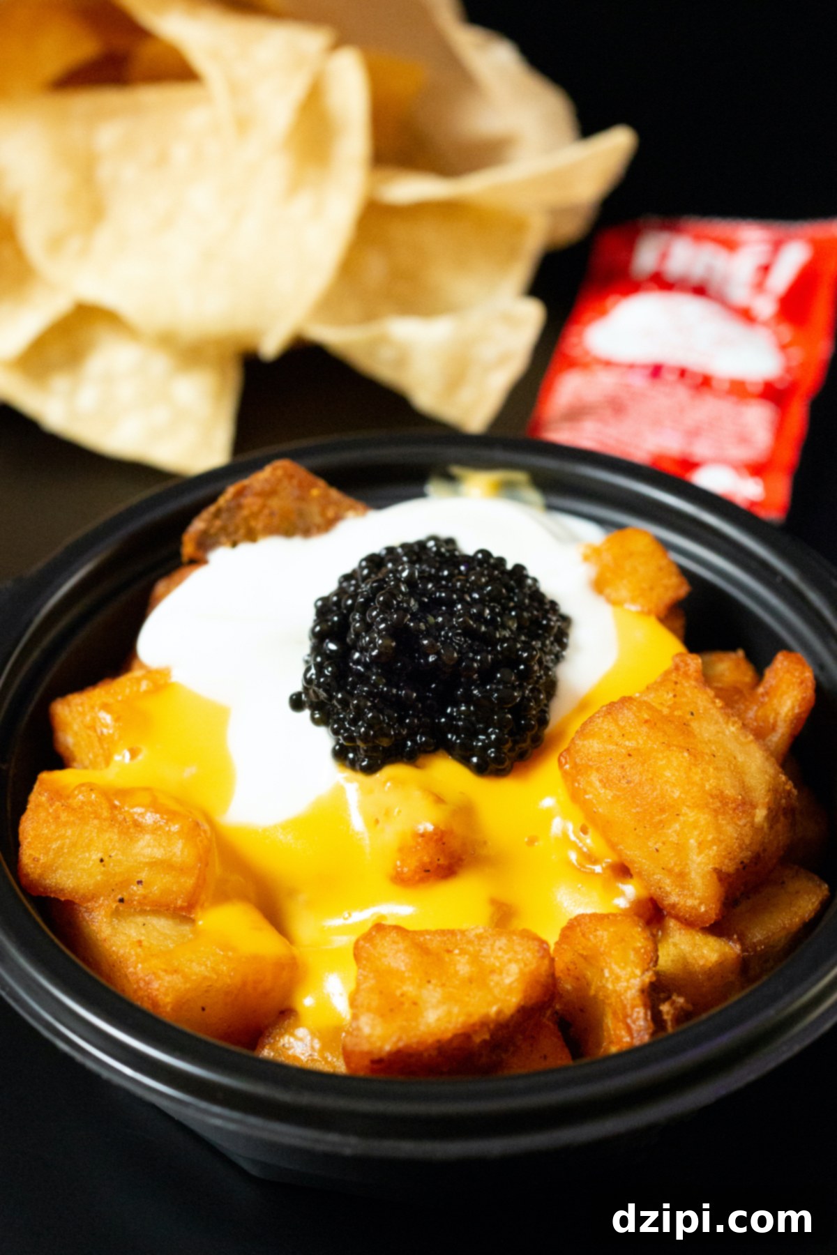 Serving Caviar: A Connoisseur's Guide 6 A bowl of Taco Bell cheesy fiesta potatoes generously topped with caviar, with tortilla chips blurred in the background.