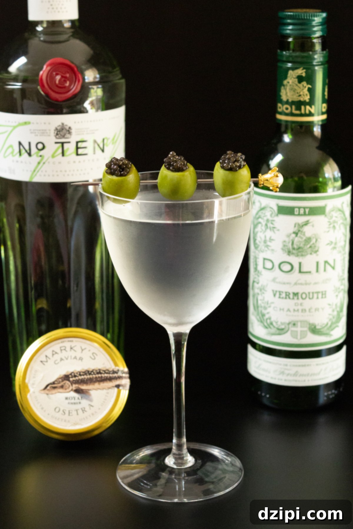 Serving Caviar: A Connoisseur's Guide 9 A martini glass with three caviar-stuffed green olives on a cocktail pick, with a bottle of gin, a tin of Royal Osetra caviar, and a bottle of dry vermouth in the background.